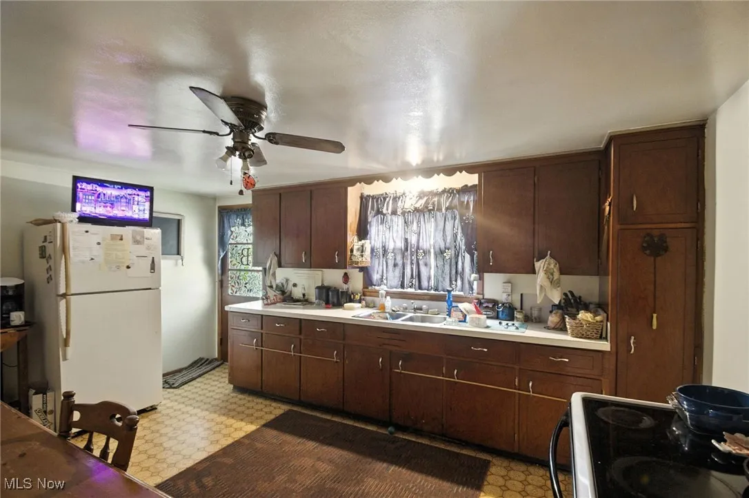 Kitchen with light flooring, freestanding refrigerator, electric range, and light countertops