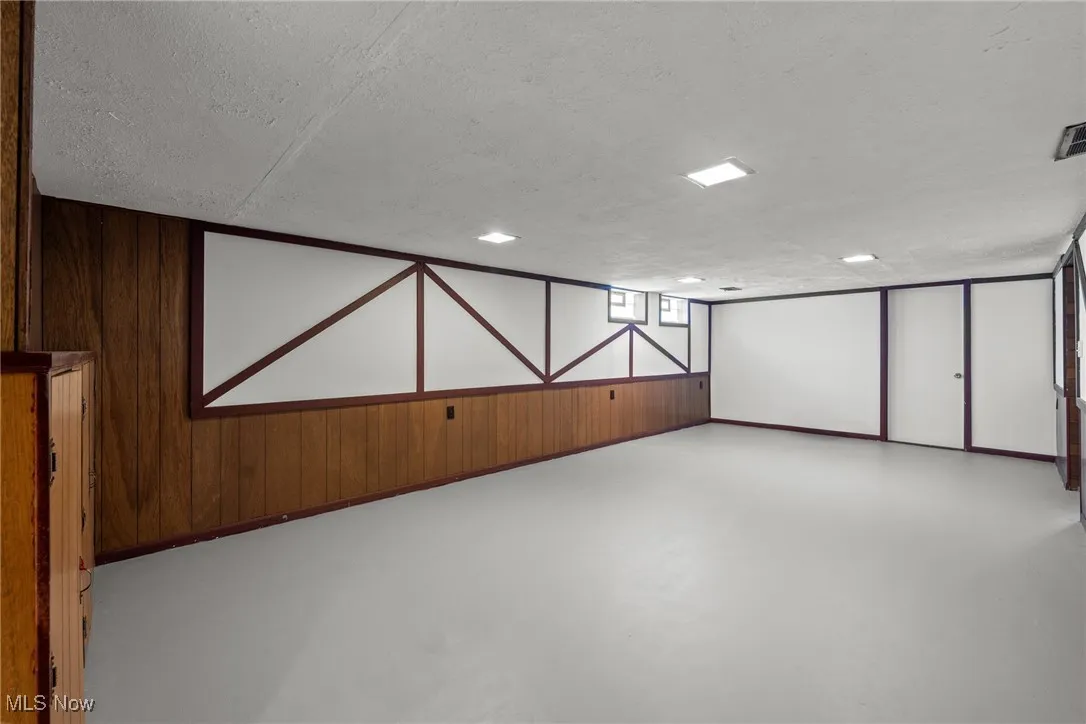 Basement with wood walls and a textured ceiling