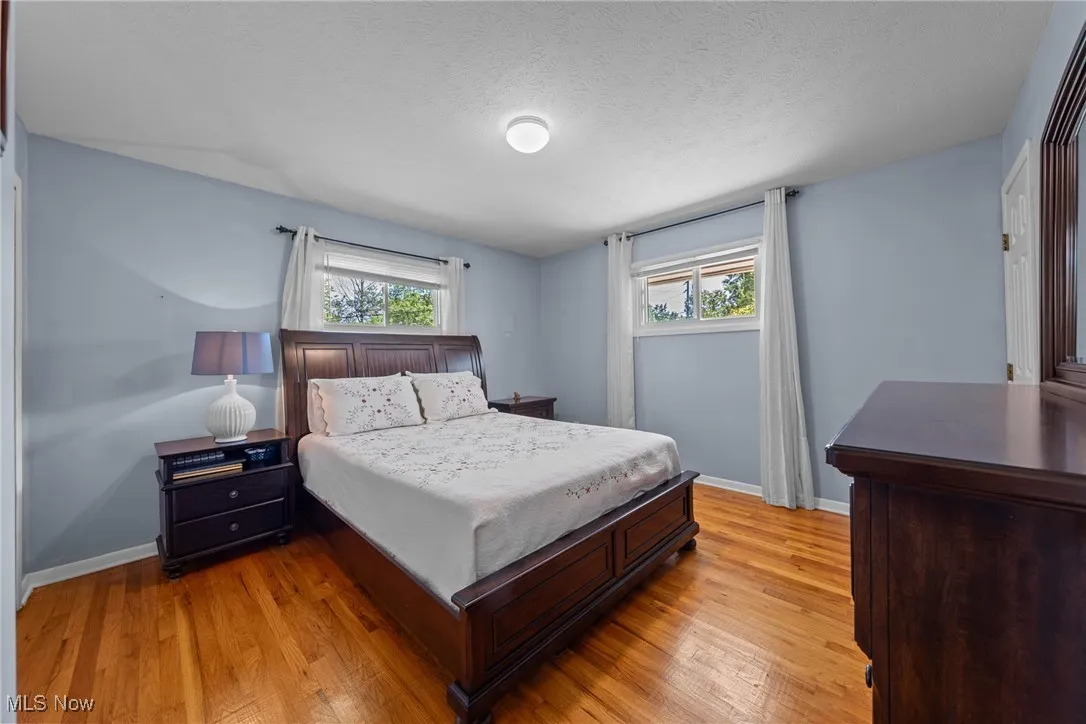 Bedroom with multiple windows, light wood finished floors, and a textured ceiling