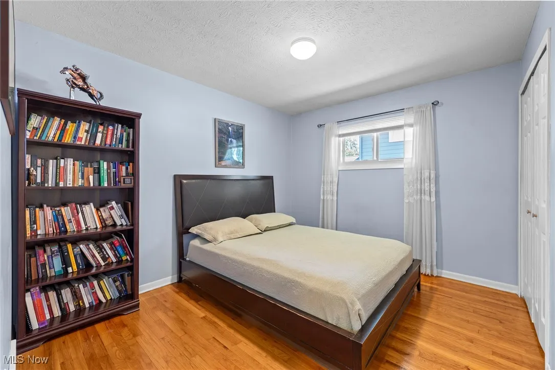 Bedroom featuring a textured ceiling, a closet, and wood finished floors