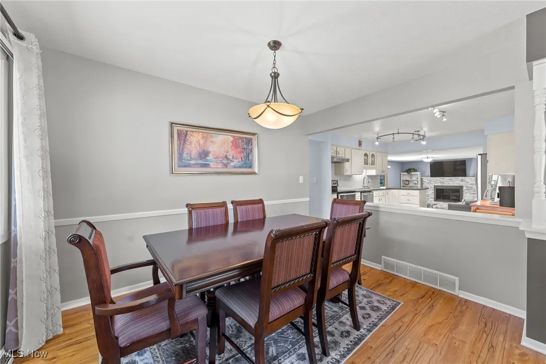 Dining room featuring light wood-style floors, rail lighting, and a fireplace