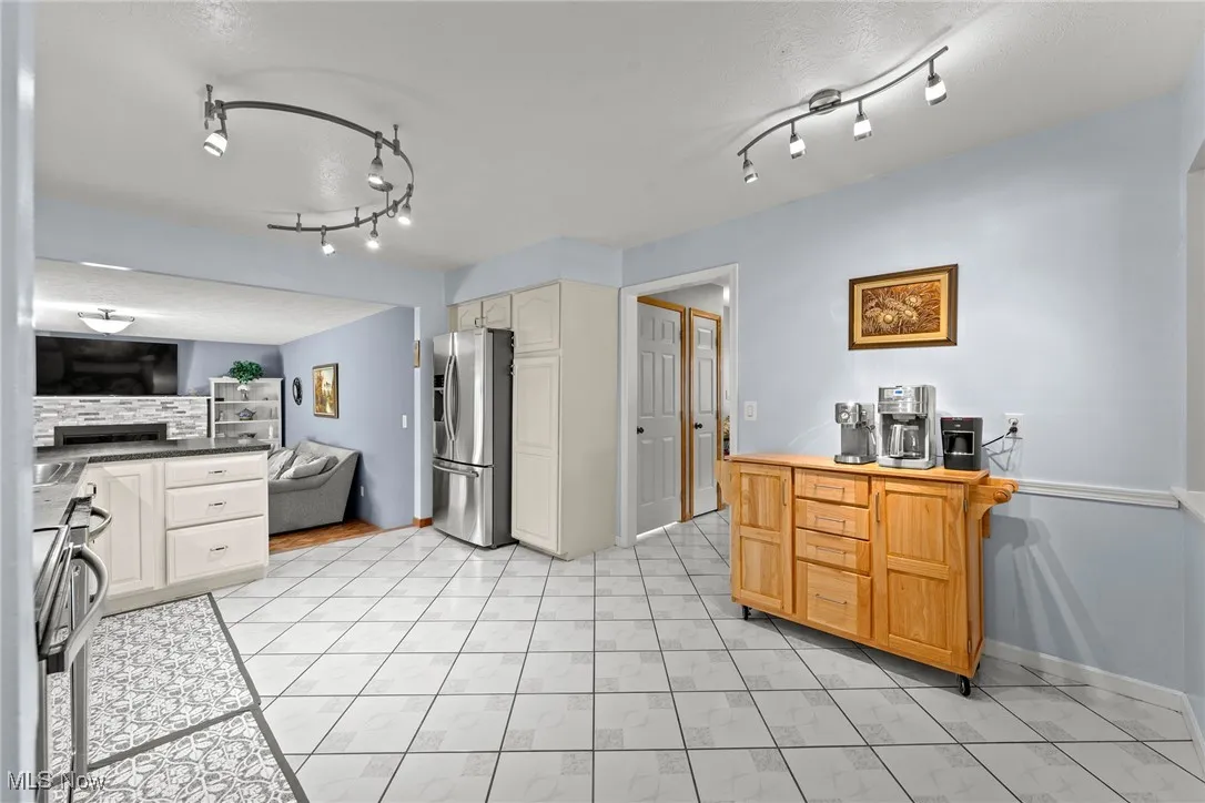 Kitchen with a fireplace, stainless steel fridge, open floor plan, decorative backsplash, and dark countertops