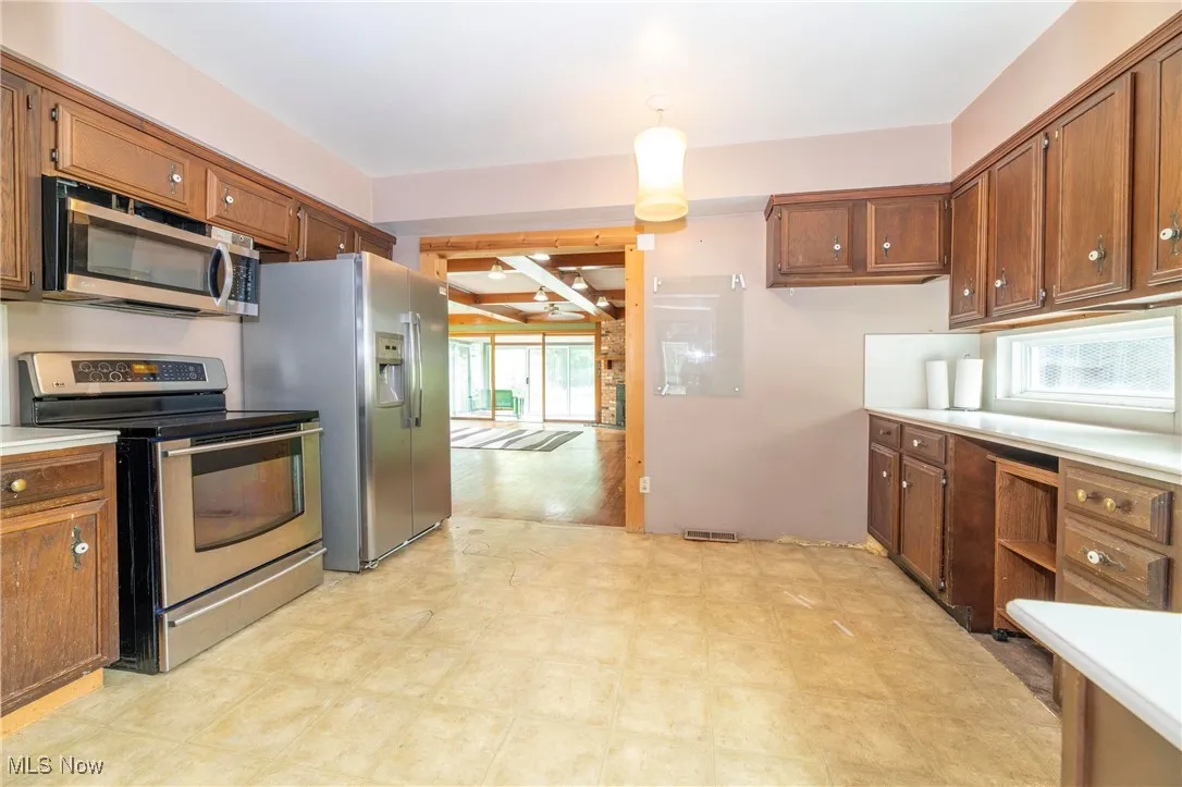 Kitchen featuring appliances with stainless steel finishes, brown cabinetry, and tile flooring