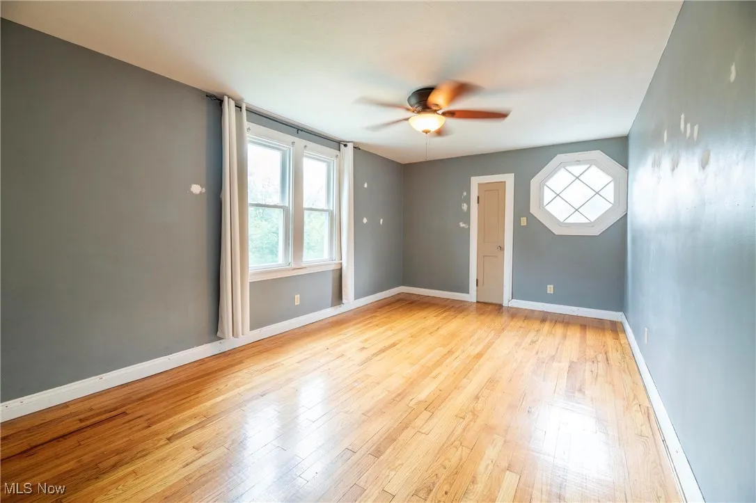 Upstairs bedroom with ceiling fan and hardwood flooring