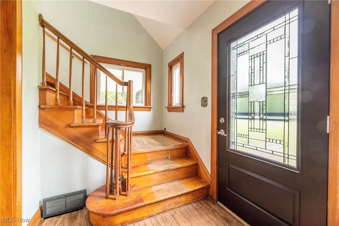 Foyer entrance featuring stairway, vaulted ceiling, and hardwood floors
