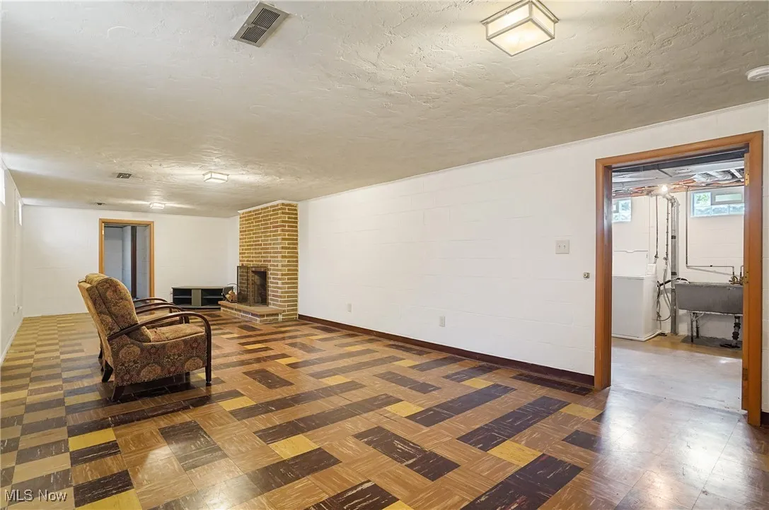 Unfurnished living room featuring a textured ceiling, concrete block wall, tile patterned floors, a fireplace, and washer / dryer