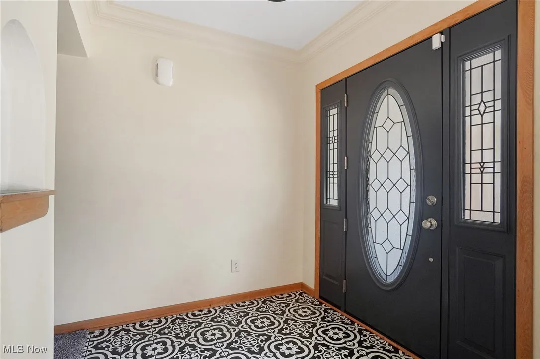 Foyer entrance featuring crown molding and baseboards