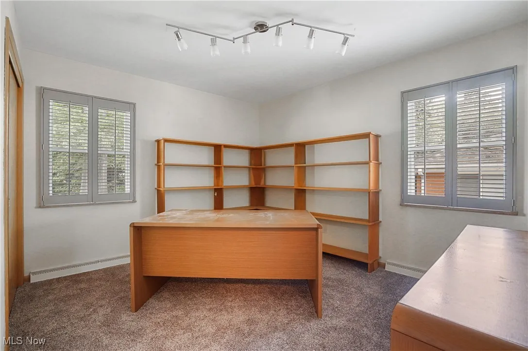 Home office with dark carpet, a baseboard heating unit, and rail lighting