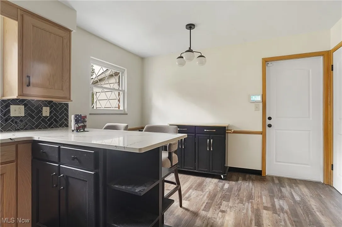 Kitchen featuring tasteful backsplash, light wood-style floors, a peninsula, and hanging light fixtures