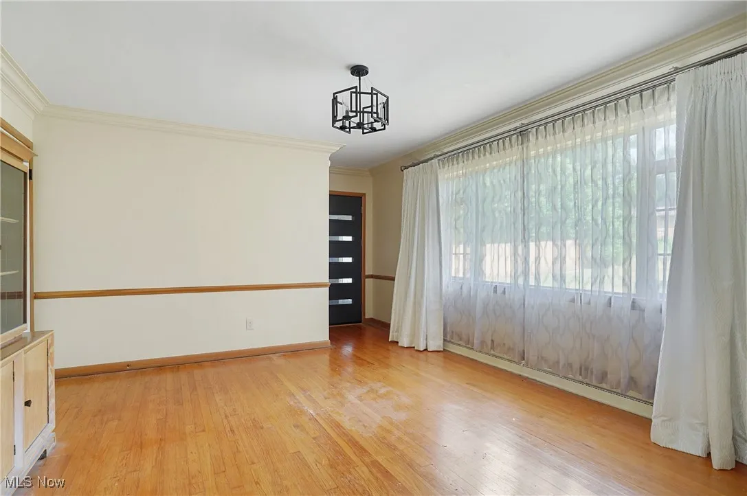 Spare room with ornamental molding, light wood-type flooring, a chandelier, and a baseboard heating unit