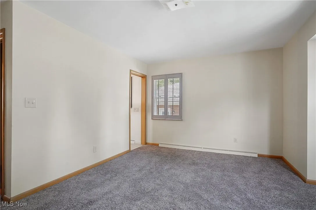 Unfurnished room featuring carpet floors and a baseboard radiator