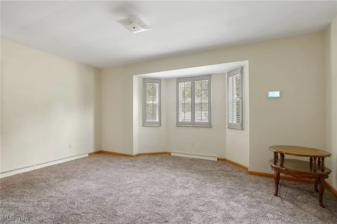 Unfurnished room with carpet and baseboard heating