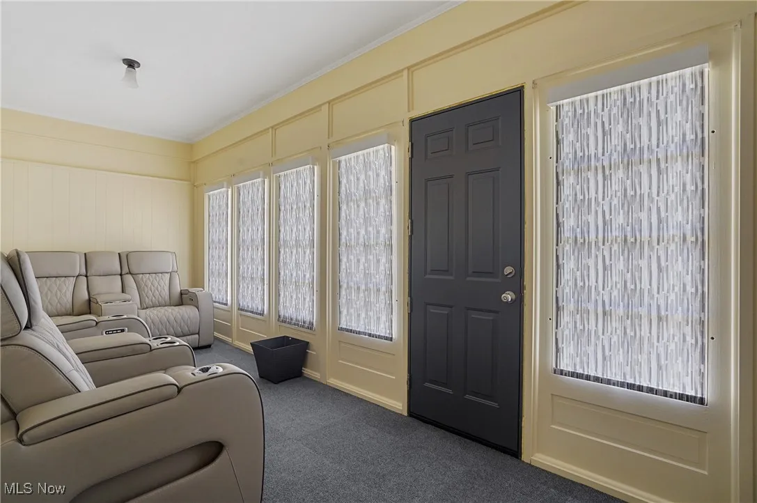 Living room with dark colored carpet, crown molding, and a decorative wall