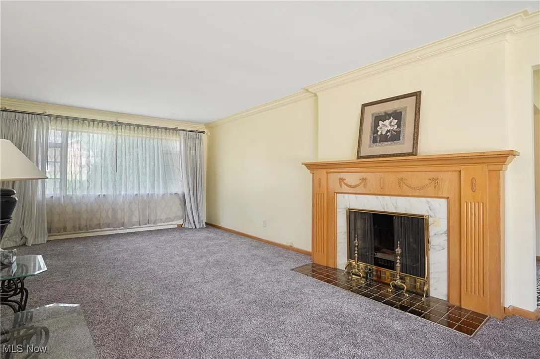 Unfurnished living room with carpet flooring, crown molding, and a fireplace