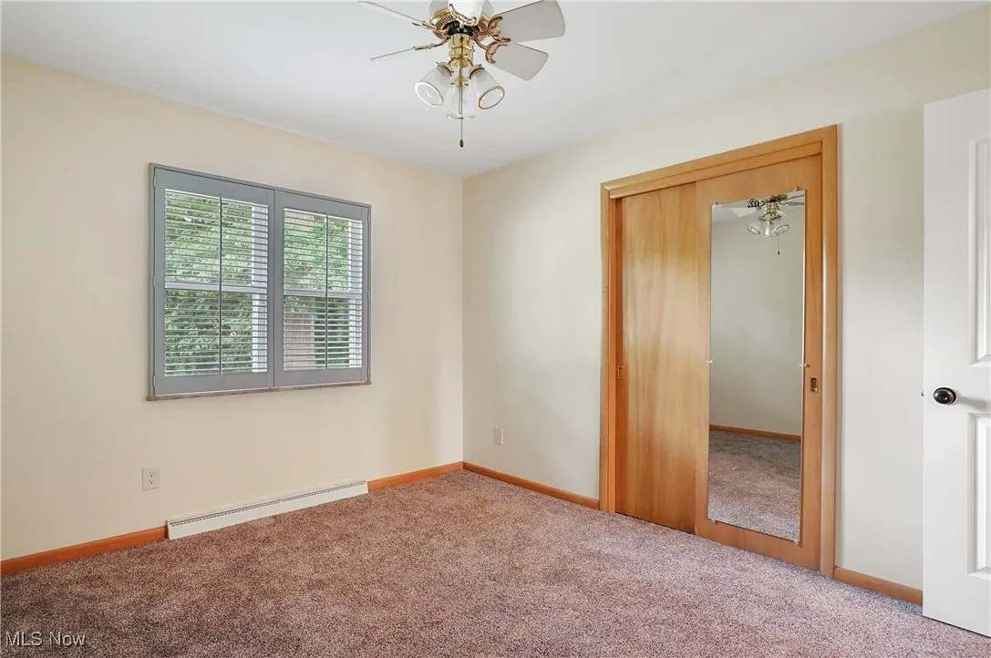 Carpeted spare room with baseboard heating and ceiling fan