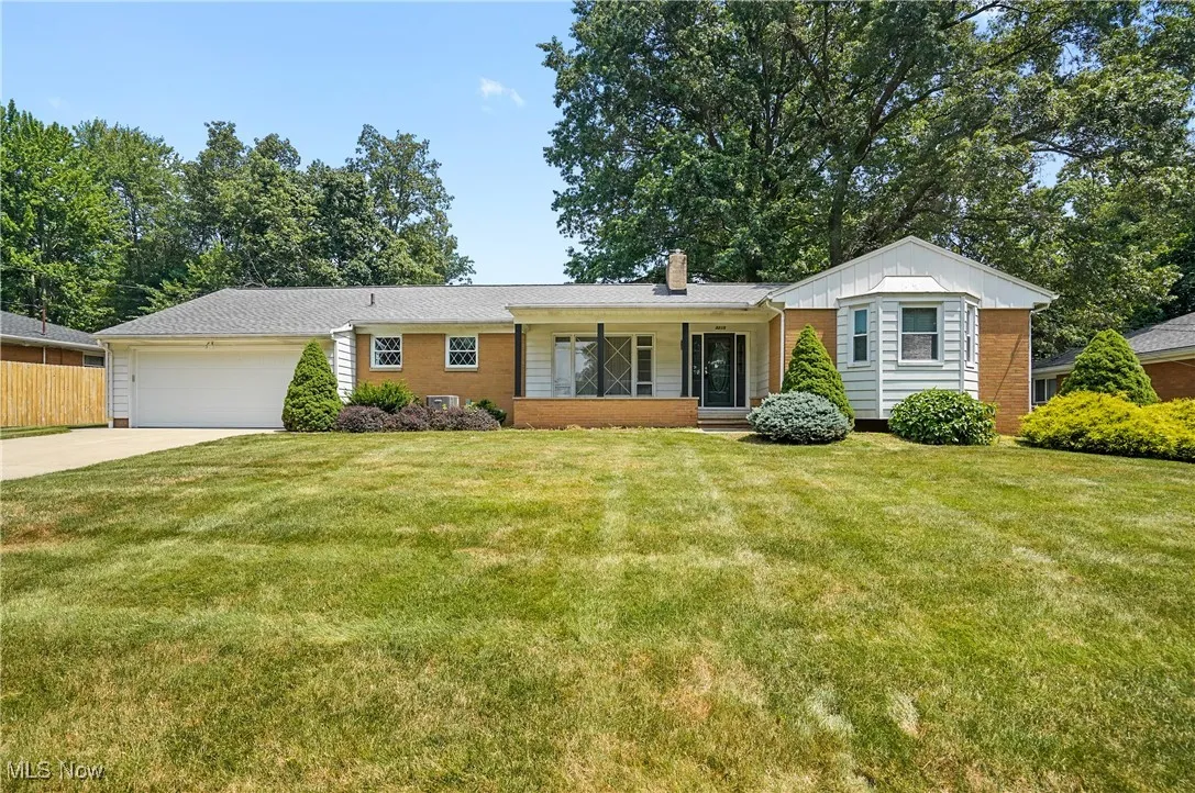 Ranch-style house with concrete driveway, a chimney, an attached garage, and brick siding