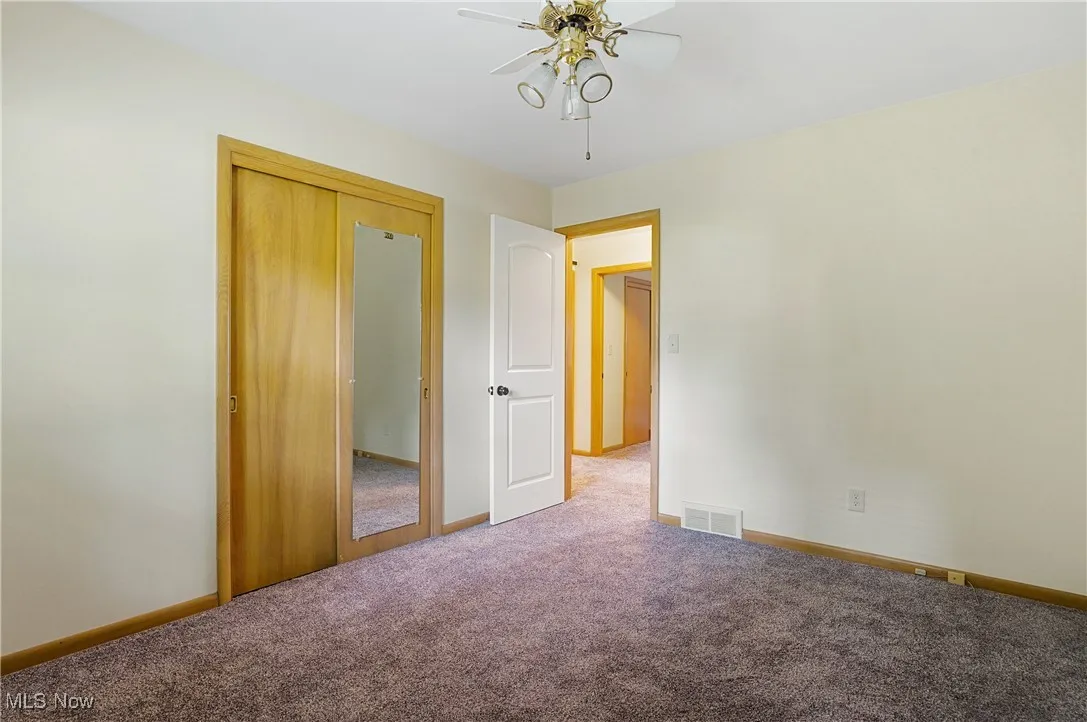 Unfurnished bedroom featuring carpet flooring, a ceiling fan, and a closet