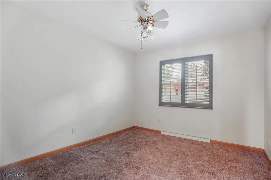 Spare room with carpet flooring, a ceiling fan, and a baseboard radiator