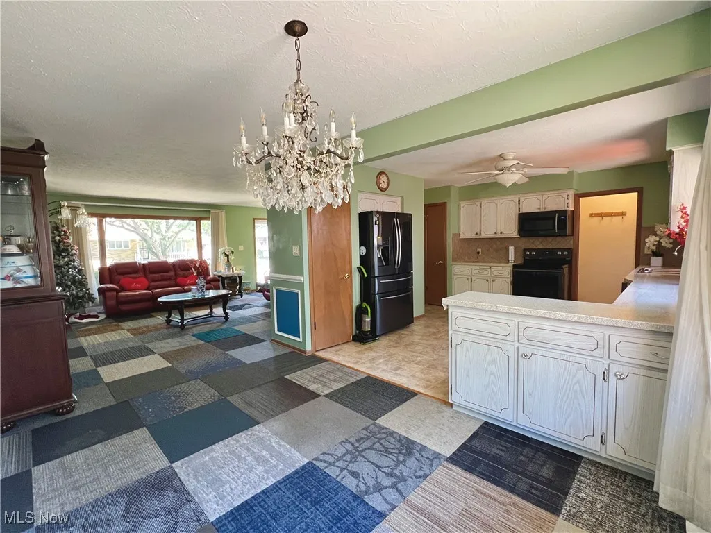 Kitchen with black appliances, open floor plan, a peninsula, light countertops, and a textured ceiling