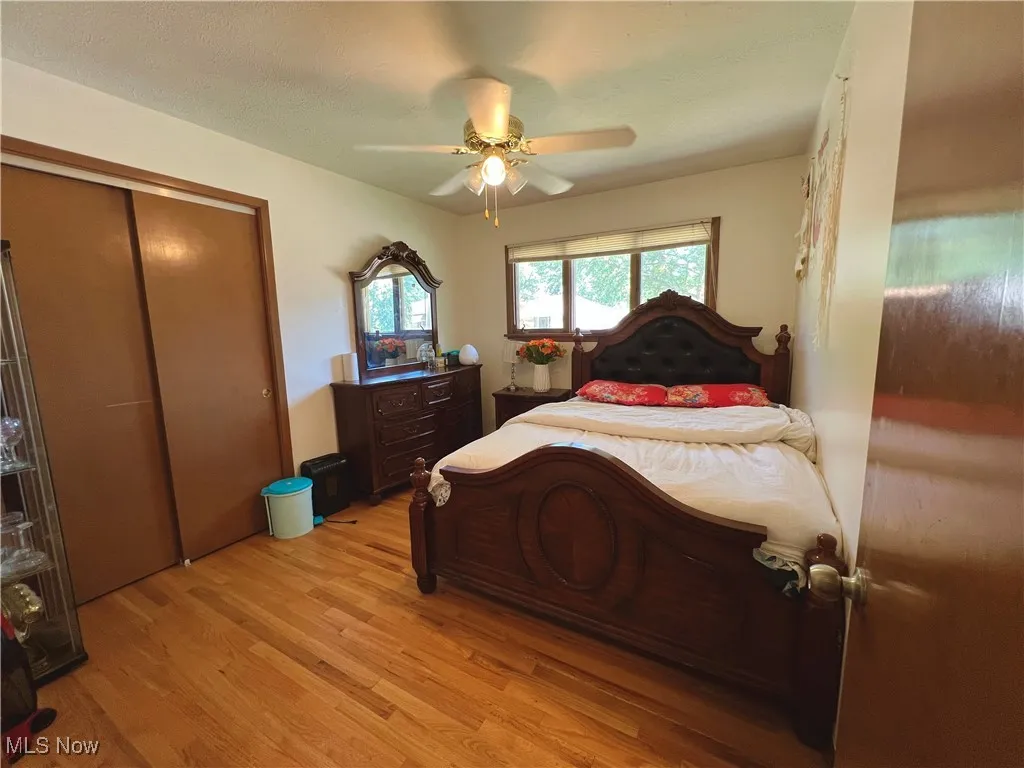 Bedroom with light wood-style floors, ceiling fan, a closet, and a textured ceiling