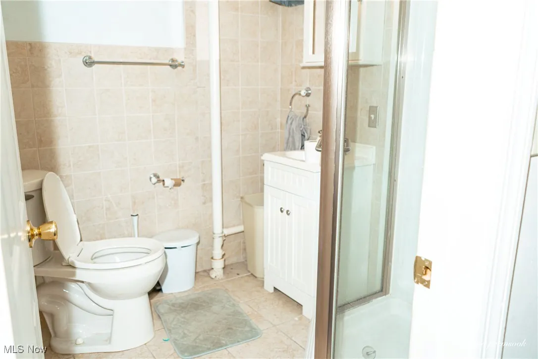 Full bathroom with tile walls, a stall shower, tile patterned floors, and vanity
