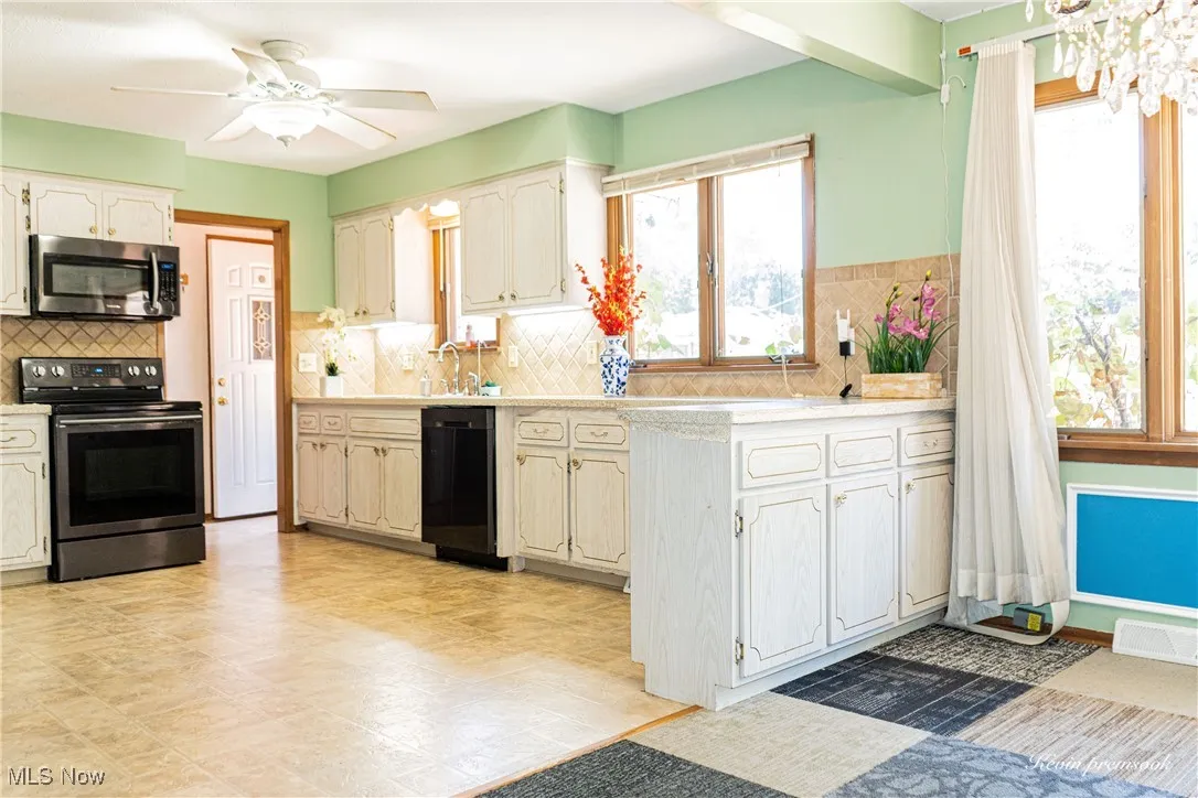 Kitchen featuring electric range oven, light countertops, stainless steel microwave, dishwasher, and decorative backsplash