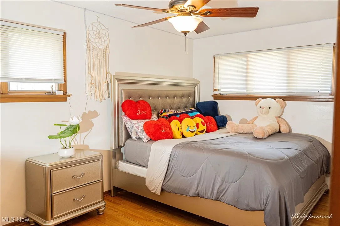 Bedroom featuring wood finished floors, multiple windows, and ceiling fan