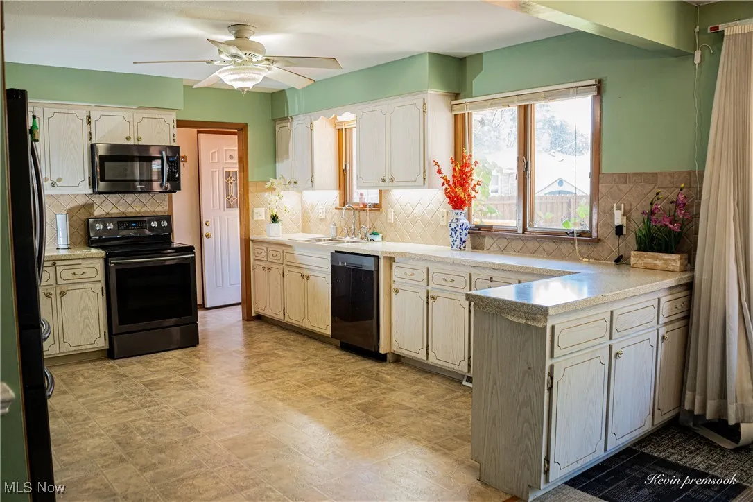 Kitchen with stainless steel appliances, light countertops, ceiling fan, and a peninsula