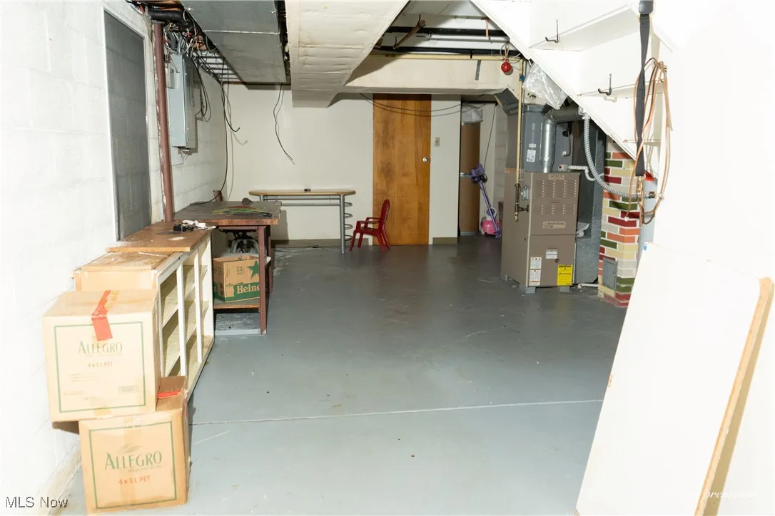 Unfinished below grade area with heating unit and electric panel