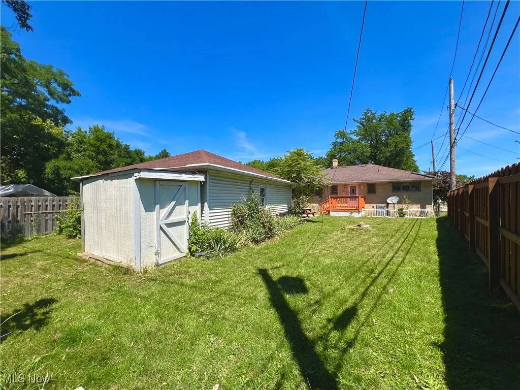 Fenced backyard featuring a storage unit and a deck