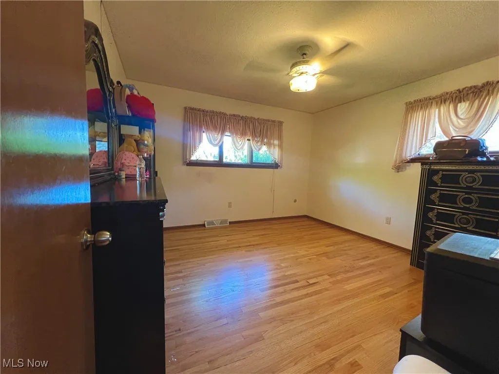 Unfurnished bedroom with light wood-style flooring, a textured ceiling, and ceiling fan