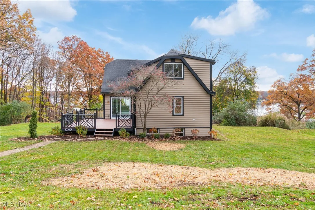 Back of property with a wooden deck and a lawn