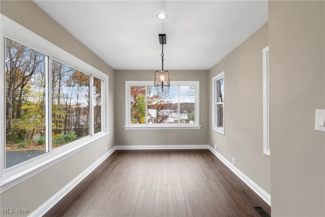 Unfurnished dining area featuring dark wood-type flooring and baseboards