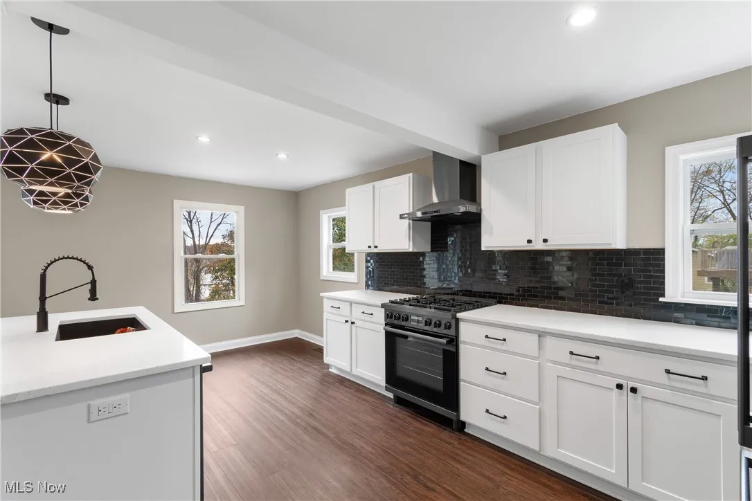 Kitchen featuring range with gas stovetop, recessed lighting, dark wood-style flooring, wall chimney range hood, and decorative backsplash