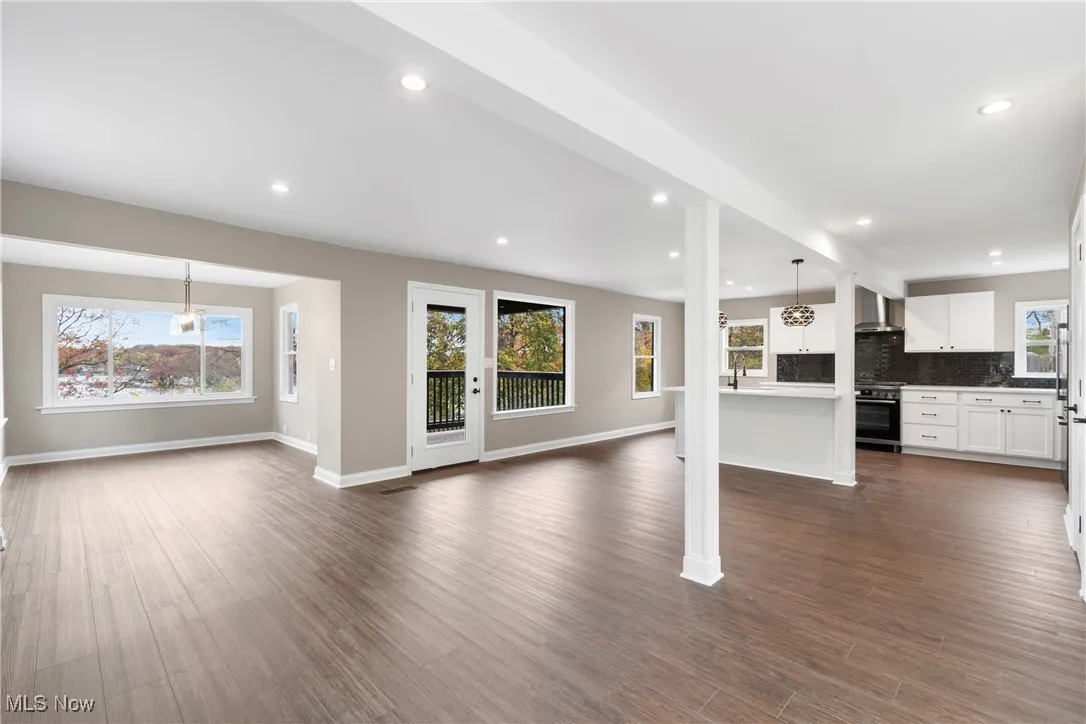 Unfurnished living room with dark wood-style flooring, recessed lighting, and ornate columns