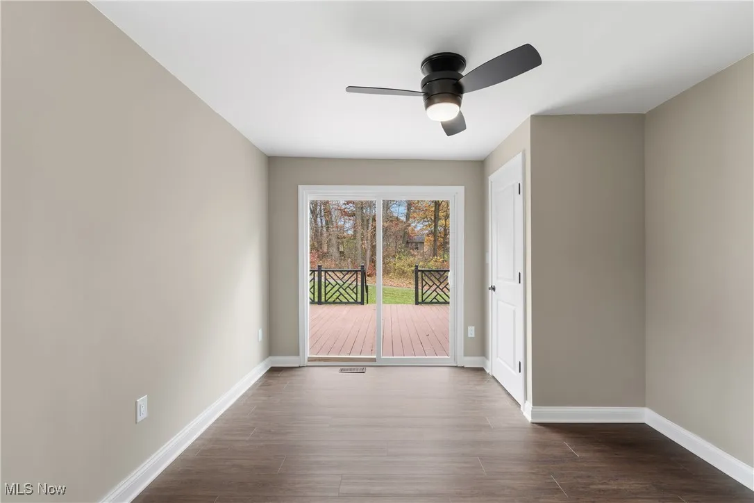 Unfurnished room with ceiling fan and dark wood-type flooring