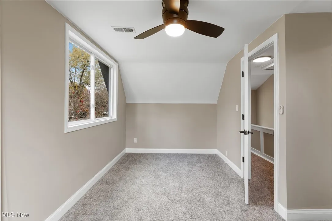 Additional living space featuring carpet flooring, vaulted ceiling, and ceiling fan
