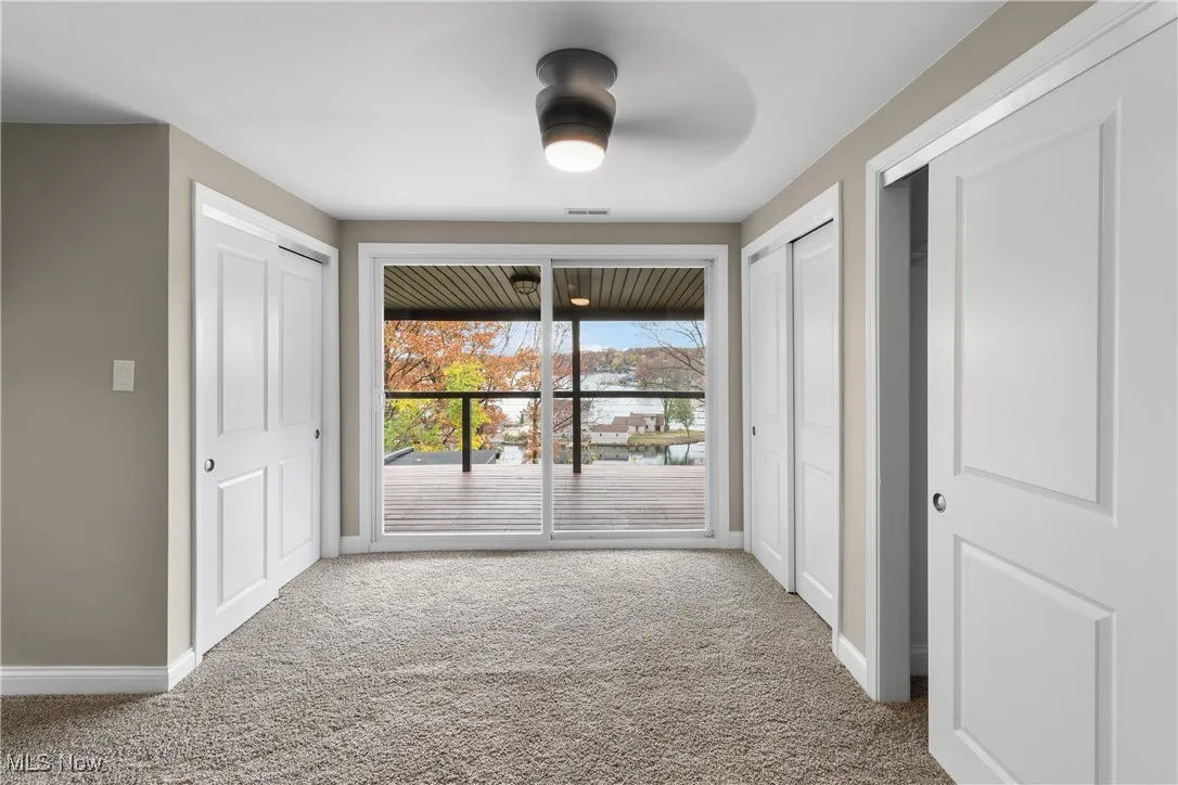 Unfurnished bedroom with multiple closets, carpet, access to outside, and ceiling fan