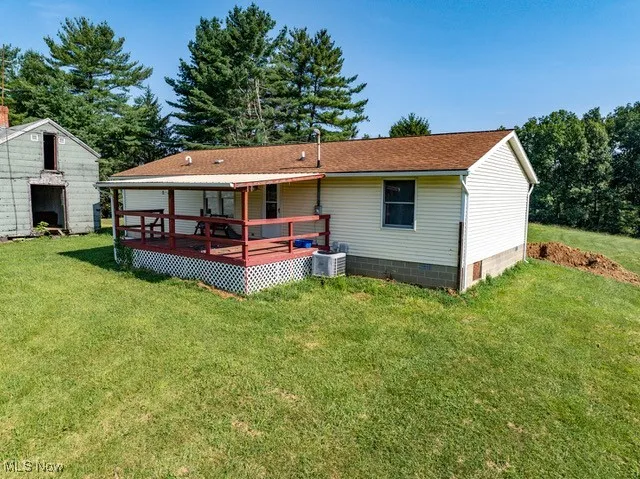 Back of property with a wooden deck, a lawn, roof with shingles, and crawl space