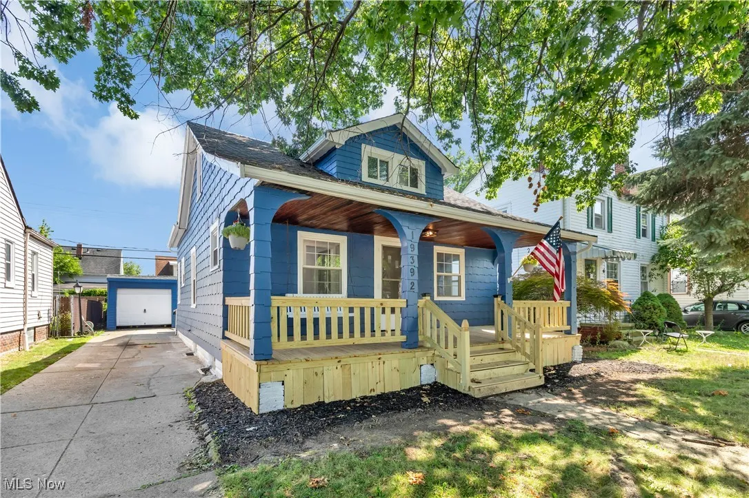 Bungalow-style home featuring a porch, an outdoor structure, and a detached garage