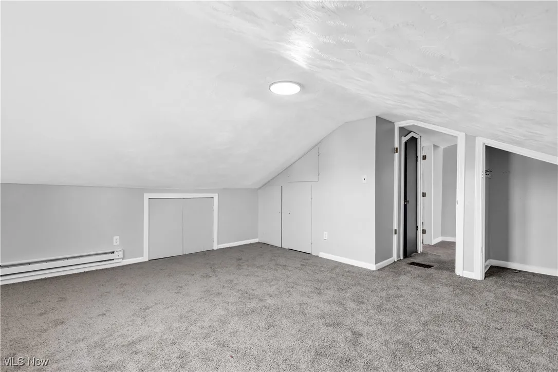 Bonus room with carpet, baseboard heating, a textured ceiling, and lofted ceiling