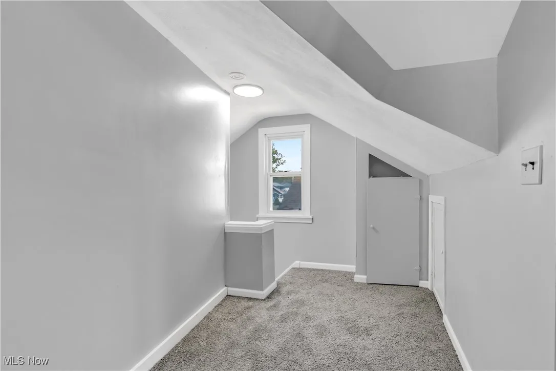 Additional living space with carpet flooring and vaulted ceiling