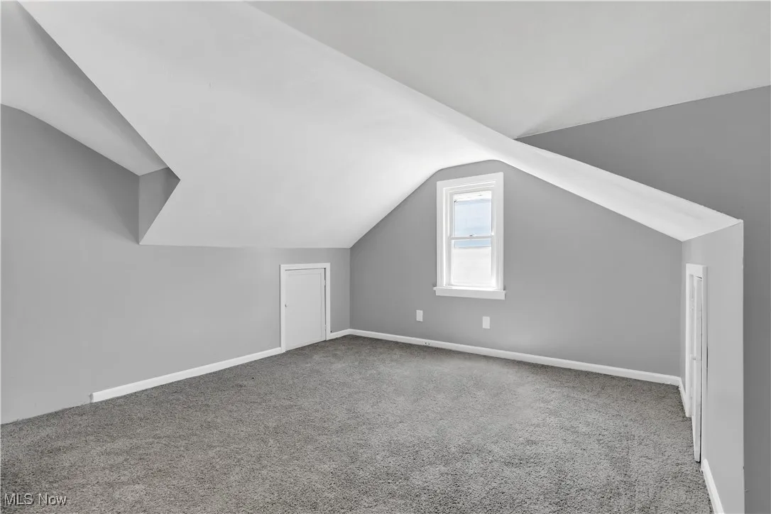 Additional living space with vaulted ceiling and carpet flooring
