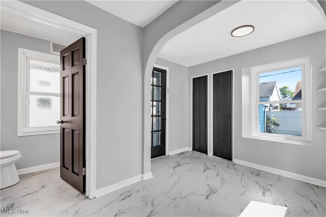 Entrance foyer featuring arched walkways and light marble finish flooring