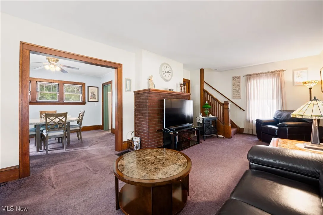 Carpeted living room featuring stairway and ceiling fan