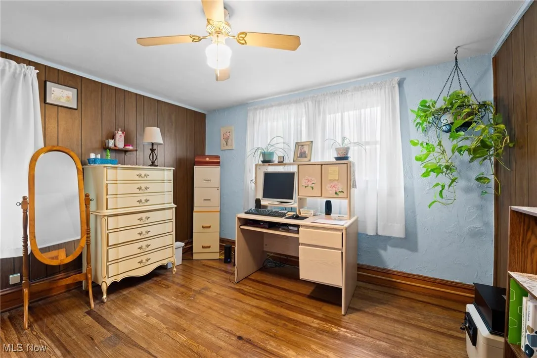 Home office with wooden walls, wood finished floors, and a ceiling fan