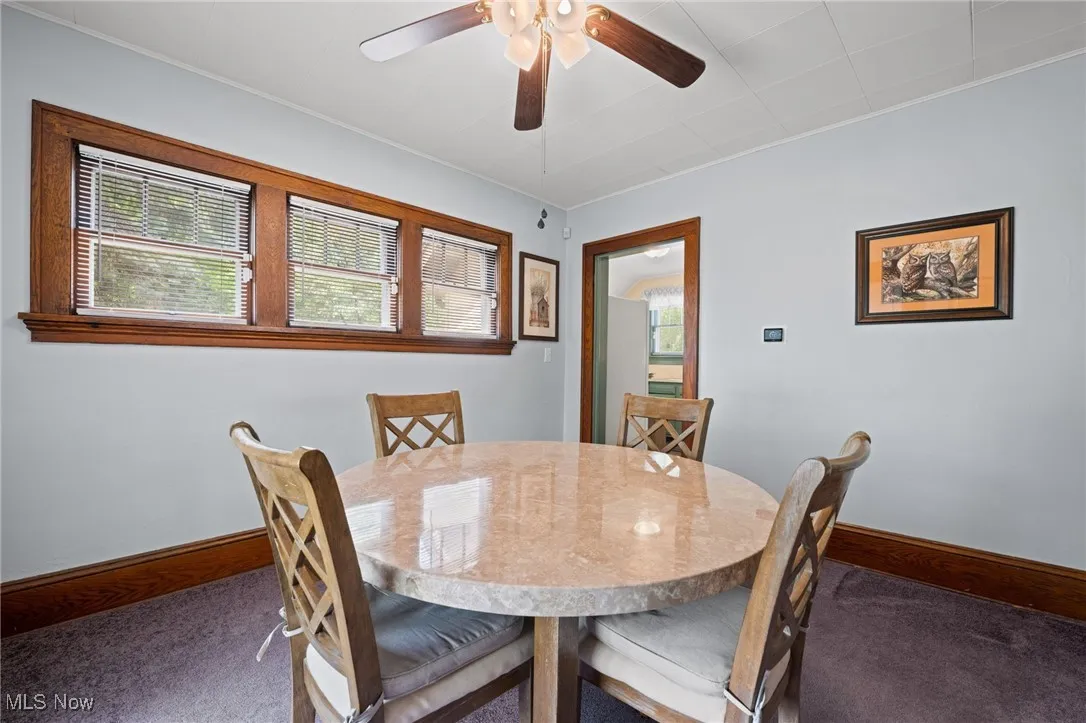 Dining area with ceiling fan and ornamental molding