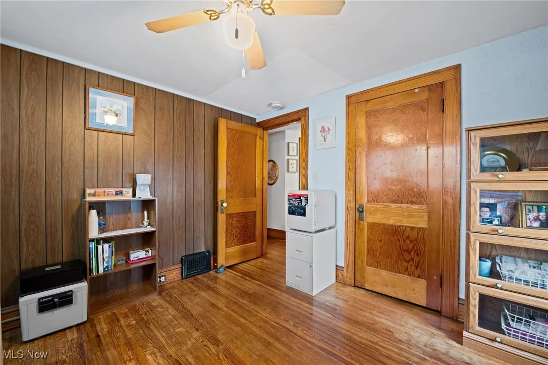 Bedroom featuring wood finished floors, wood walls, and ceiling fan