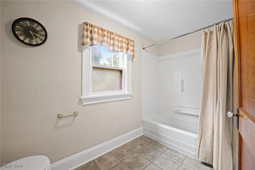 Full bath with shower / bath combination with curtain and tile patterned flooring