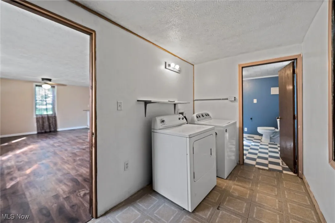 Laundry room with a textured ceiling, separate washer and dryer, and tile patterned floors
